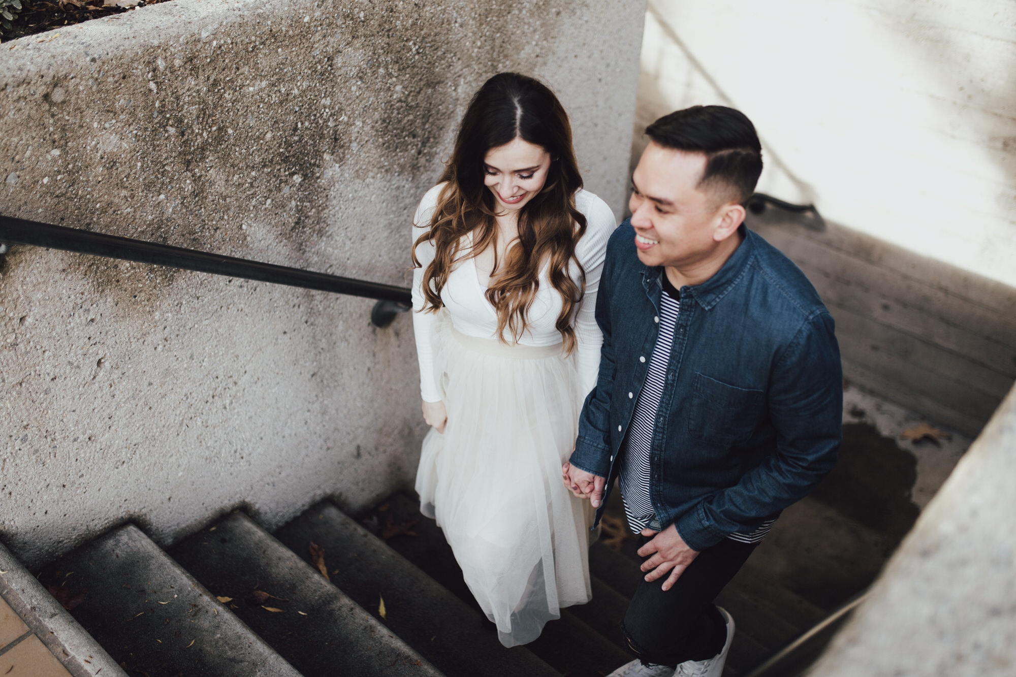 candid engagement photos on staircase by pomona university